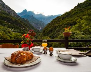a table with a croissant and coffee and a view of mountains at Hotel Al Verde in Mandello del Lario