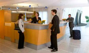 eine Gruppe von Personen, die an einem Schalter auf einem Flughafen stehen in der Unterkunft GenoHotel Karlsruhe in Karlsruhe