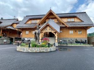 a log cabin with a statue in front of it at Zbojnicky penzion in Jasenica