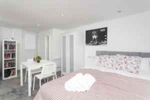 a white bedroom with a bed and a table at Leeds House in Leeds