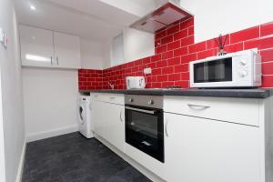 a kitchen with white cabinets and red tiles at Leeds House in Leeds