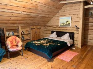 ein Schlafzimmer mit einem Bett und einem Stuhl in einer Hütte in der Unterkunft Adeles sodyba in Sturmai