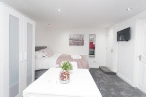 a white room with two beds and a tv at Leeds House in Leeds