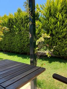 un banco de madera sentado en el césped con arbustos en Villa Maria 2, en Toroni