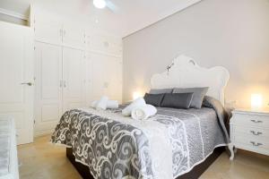 a white bedroom with a bed with a black and white bedspread at Duque de Hornachuelos, parking en pleno centro in Córdoba