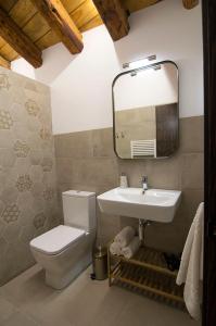 Un baño con lavabo, inodoro y espejo. en Casa Barrena, en Albarracín