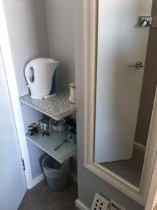 a corner of a bathroom with a mirror and shelves at Southville Guest House in Weymouth