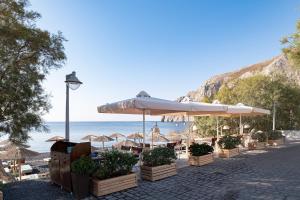 a beach with umbrellas and chairs and the ocean at Santorini Crystal Blue Boutique Hotel in Kamari