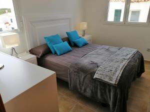 1 dormitorio con 1 cama grande con almohadas azules en VILLA DIPLOMADO (RELAX EN EL PARAISO), en Es Mercadal
