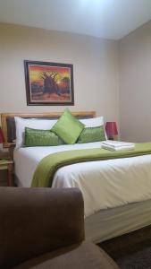 a bedroom with two beds with green pillows at African Sky Guest House in Krugersdorp