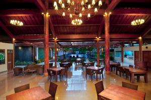 um restaurante com mesas e cadeiras de madeira e um lustre em Febri's Hotel & Spa em Kuta