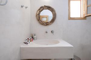 a white sink sitting under a mirror in a bathroom at Santorini Crystal Blue Boutique Hotel in Kamari
