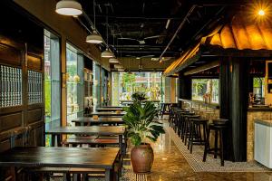 um restaurante com mesas e cadeiras de madeira e um vaso de plantas em BAYYA HOTEL PHU QUOC em Duong Dong