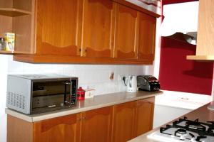 a kitchen with wooden cabinets and a microwave at Hartland Apartments - near Cliffs Pavilion in Southend-on-Sea