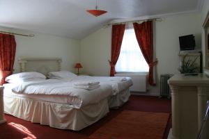 two beds in a bedroom with red curtains at Hartland Apartments - near Cliffs Pavilion in Southend-on-Sea