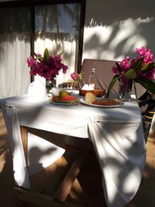 
a table with a plate of food and a vase of flowers at Kinazi Upepo Beach Hotel in Paje
