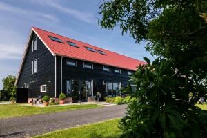 a black barn with a red roof at Hofwestdijk in Vrouwenpolder