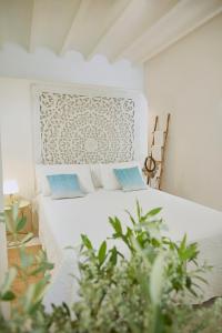 a bedroom with a white bed with blue pillows at Boho Suites Denia in Denia