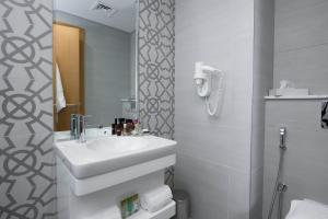 ibis Styles Manama Diplomatic Area في المنامة: حمام أبيض مع حوض ومرآة
