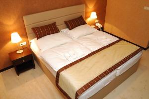 1 cama grande en una habitación de hotel con 2 lámparas en Hotel Predium, en Vráble
