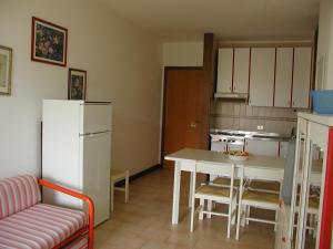 a kitchen with a table and a white refrigerator at FLATS SOLARIUM in Bibione +53 photos
