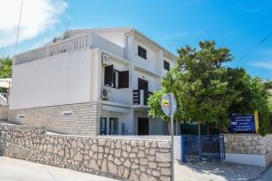 a white building with a stone wall and a tree at House Lanterna Pag in Pag