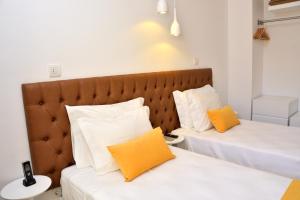 two beds with white and orange pillows in a room at Hotel Sol Algarve by Kavia in Faro