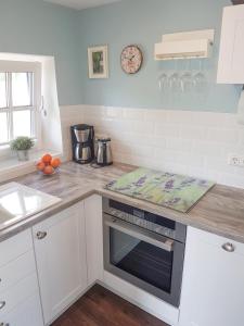 a kitchen with white cabinets and a counter with an oven at Reetferienhaus - Schaprode Hafen in Schaprode