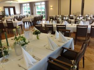 une salle à manger avec des tables et des chaises blanches dans l'établissement Hotel Restaurant Stegemann, à Saerbeck