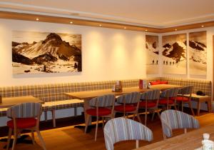 ein Restaurant mit Tischen, Stühlen und Gemälden an der Wand in der Unterkunft Hotel Garni Lärchenhof in Lech am Arlberg