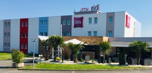 a hotel with palm trees in front of a building at Ibis Auray in Auray