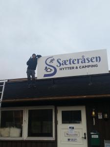 a man standing on the roof of a building at Sæteråsen Hytter & Camping Trysil in Trysil
