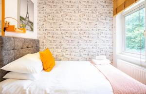 Cama blanca en habitación con pared de ladrillo en Tower Bridge Rainbow Suites, en Londres