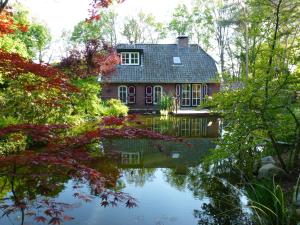 een huis weerspiegeld in het water van een vijver bij Vakantiewoning Salland in Markelo