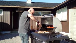 a man standing next to a barbecue grill at Sæteråsen Hytter & Camping Trysil in Trysil