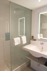 a bathroom with a shower, sink, and mirror at Novotel Wien City in Vienna
