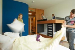 a group of people in a bedroom with a bed at Youth Hostel Beaufort in Beaufort