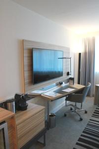 a room with a desk, chair and a television at Novotel Wien City in Vienna