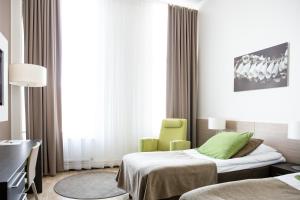 a hospital room with two beds and a green chair at Norlandia Tampere Hotel in Tampere
