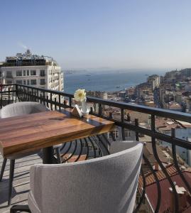 een houten tafel en stoelen op een balkon met uitzicht op de oceaan bij Juno Hotel Taksim in Istanbul