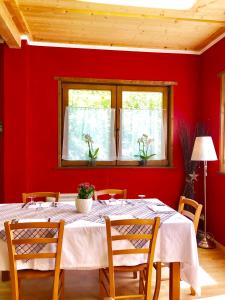 uma sala de jantar vermelha com uma mesa branca e cadeiras em Chalet Rosa dei Monti em Valprato Soana