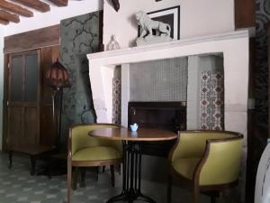 een eetkamer met een tafel en stoelen en een open haard bij 'La Ménagerie' in Châteauvieux