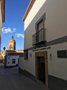 a building with a balcony and a clock tower in the background at Palacete Magistral Domínguez habitaciones in Guadix