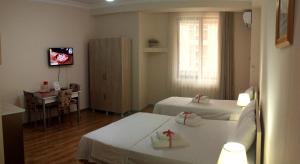 a room with two beds and a table and a television at Hotel Tao in Batumi