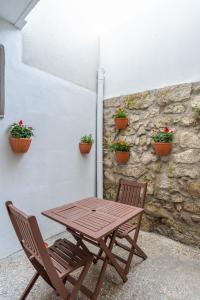 een houten tafel en stoelen naast een stenen muur met potplanten bij ZD Moreira Flats A By PortoProperties4You in Porto