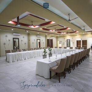 錫勞的住宿－Hotel Ecce Inn & Spa，一个带白色桌椅的大型宴会厅