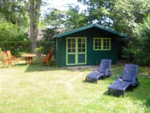 een groene schuur met twee stoelen en een tafel in een tuin bij Gästehaus Strandkonsulat in Scharbeutz