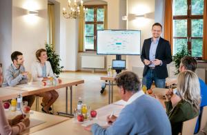 a man standing in front of a screen in a meeting room at JUFA Hotel Schloss Röthelstein in Admont