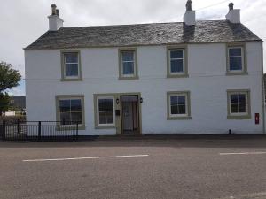 a white house with a door on a street at Modern 1 bed Apartment close to Campbeltown in Campbeltown