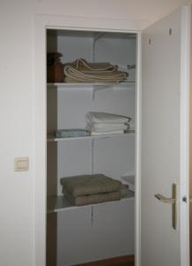 a closet with white shelves and folded towels at Oase im Park in Berlin